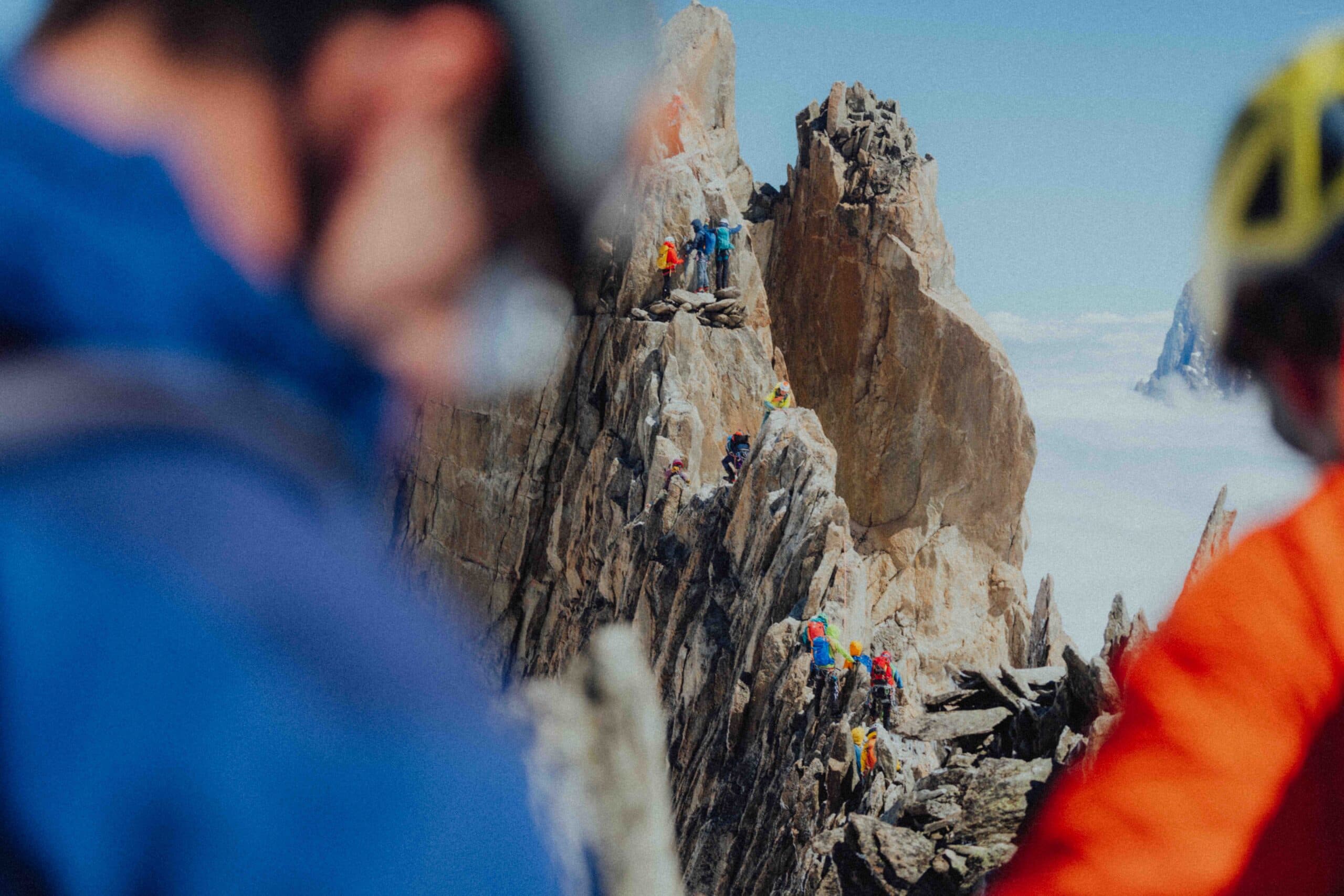 Mountaineers in colorful jackets ascending an exposed granite ridge in the Mont Blanc massif — guided alpine climbing expedition on weAltura